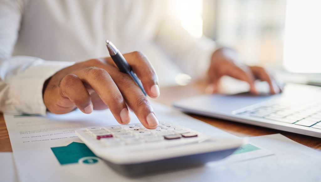person at desk using calculator and laptop