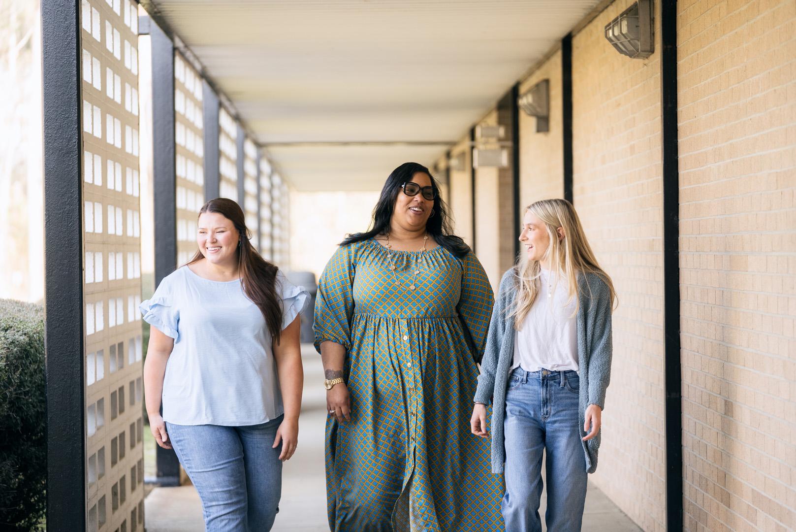 A group of three individuals is captured in motion, seemingly engaged in a leisurely stroll.